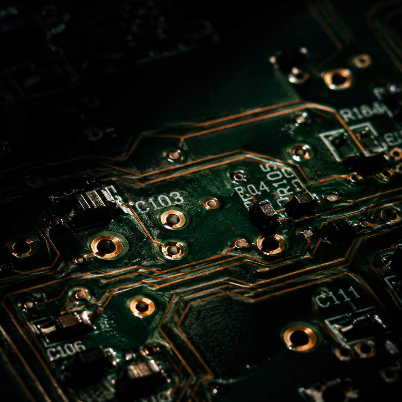Dramatically lit circuit board with copper traces and through-hole vias